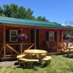 Frontier Cabin with two tables and hanging flowers, built by Amish Barn Co.