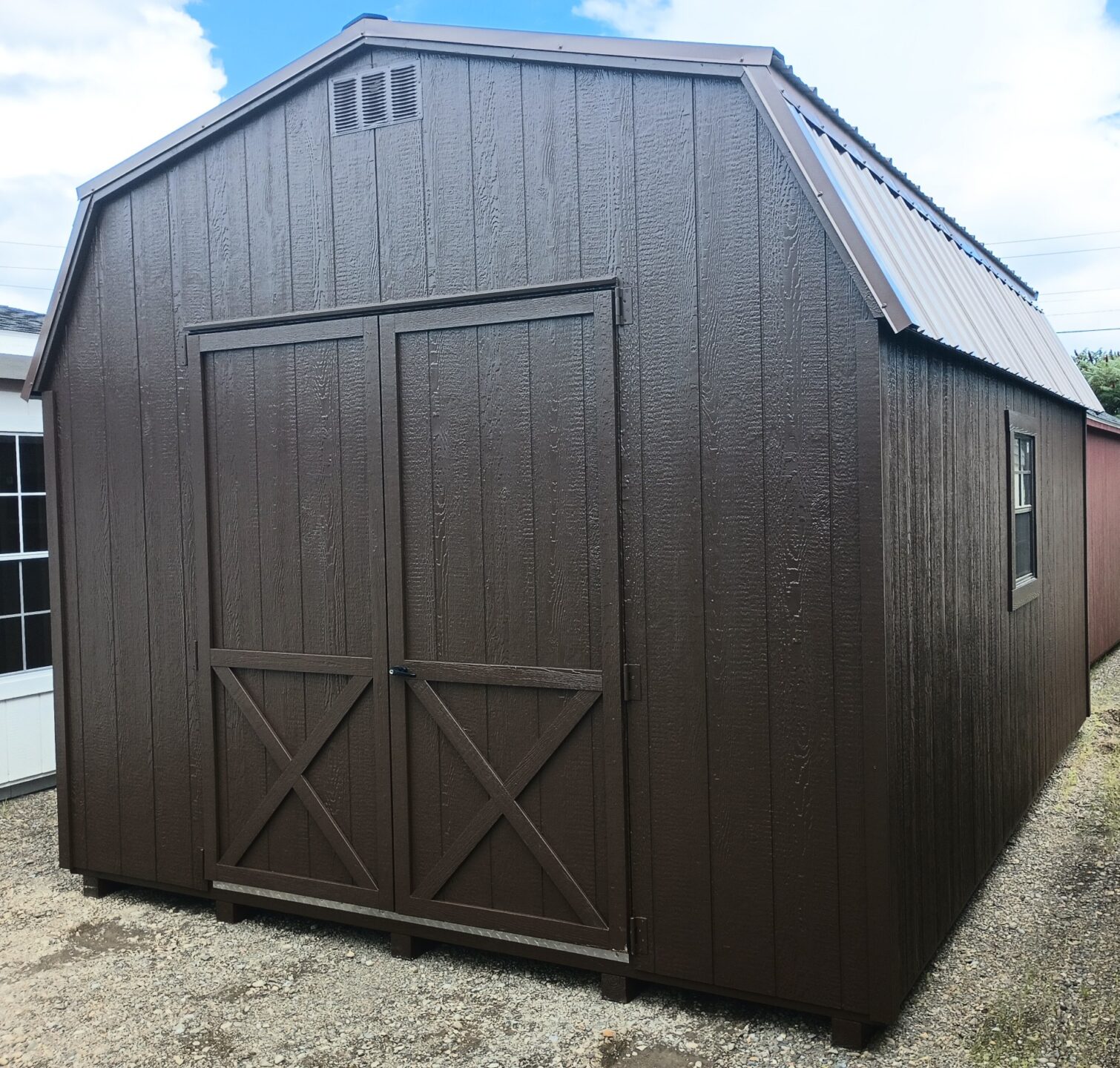 Brown shed with barn metal roof, double doors and two windows