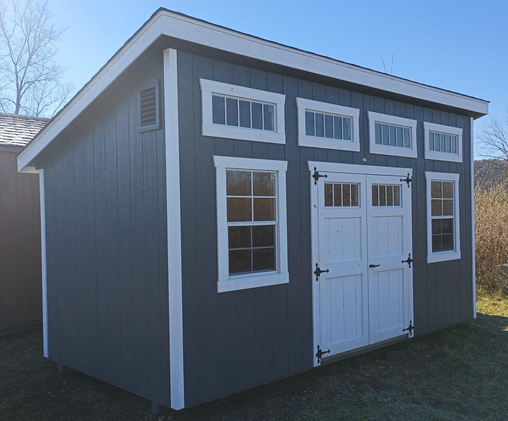 Gray Lean To with Transom Windows above Double Doors and Windows on either side of Double Doors