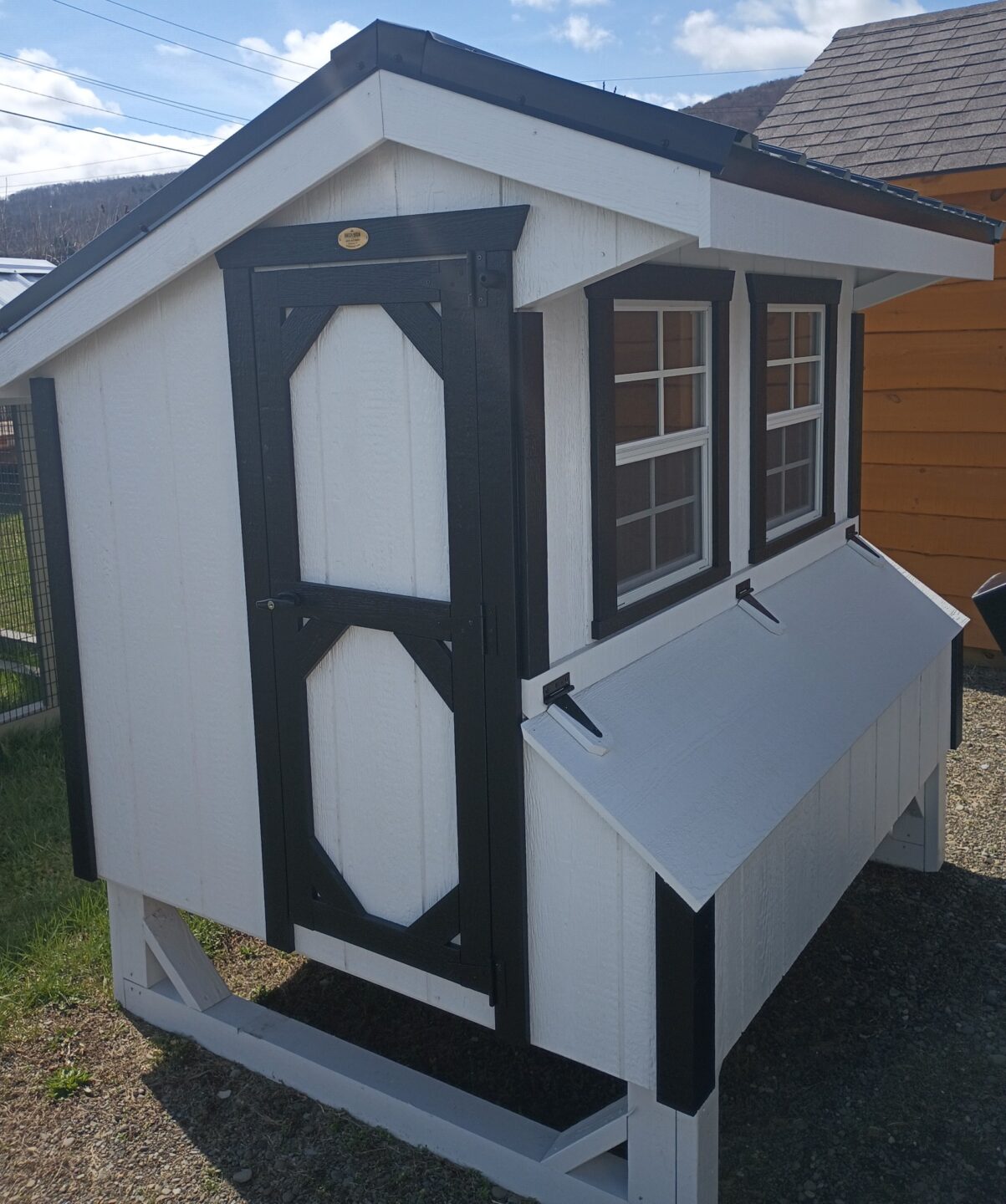 Quaker style white chicken coop with black trim, two windows and access door