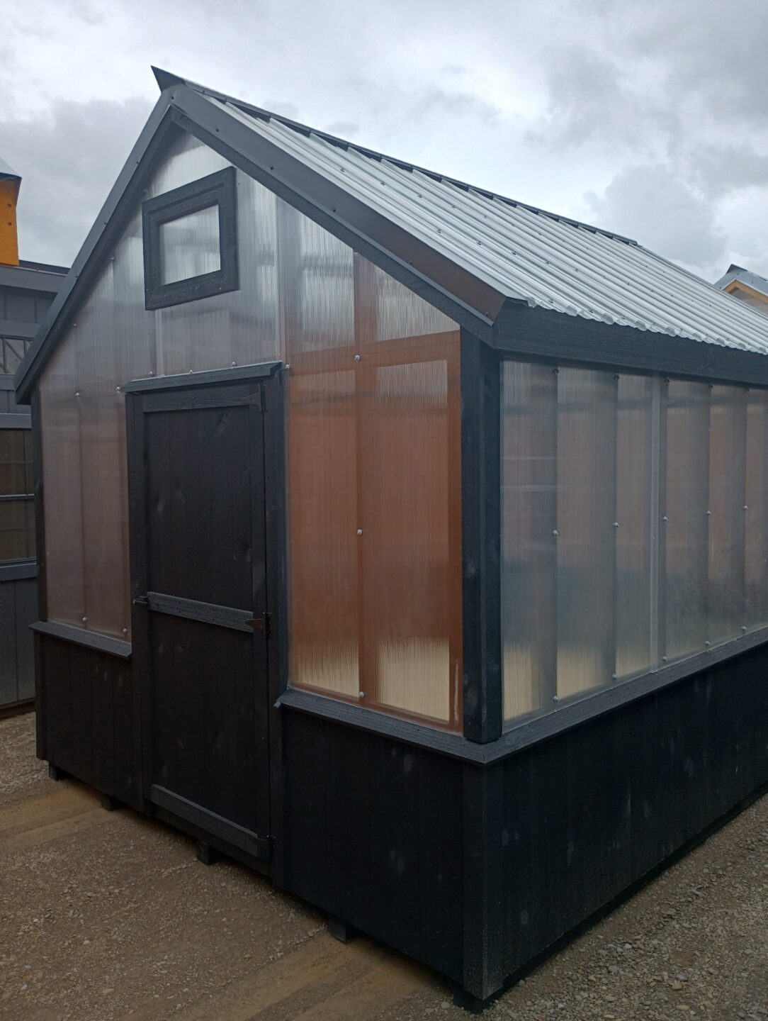 Small greenhouse with clear wall panels and 2' tongue and groove black knee wall