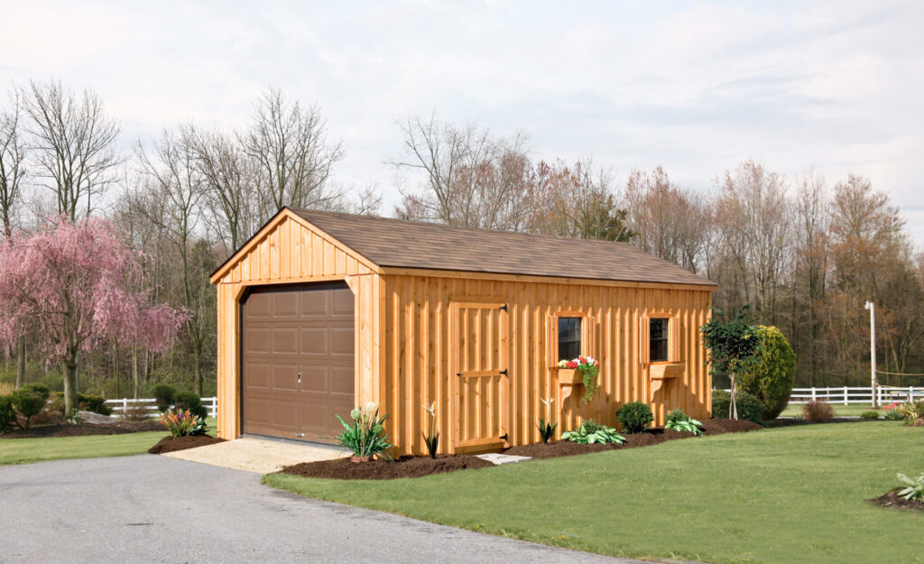 Amish-built board and batten prefab garage surrounded by beautiful landscaping