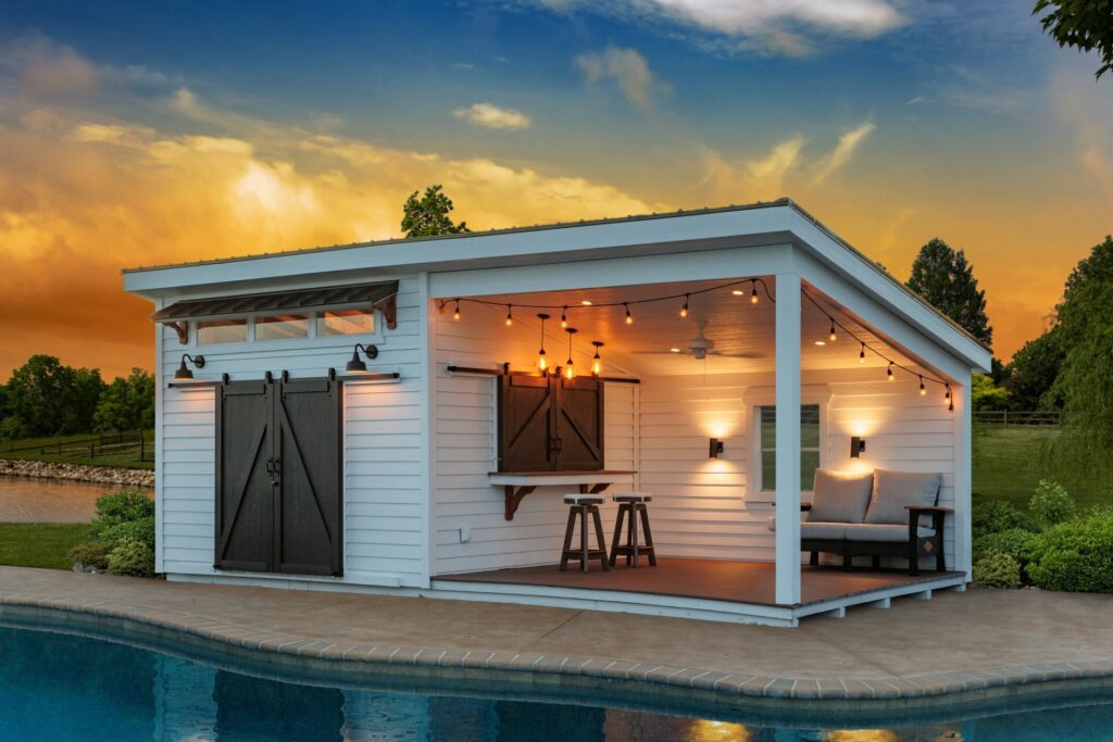 Custom-built pool house featuring bar counter and shaded seating area with a beautiful sunset backdrop. Perfect for those looking for New Scotland sheds.