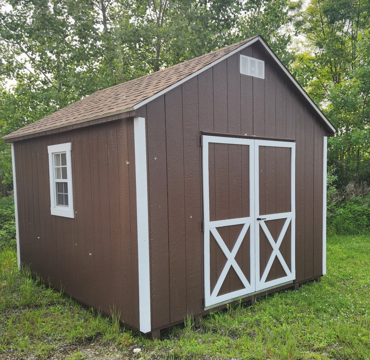 Brown shed with white trim, light brown shingles, double doors and two windows