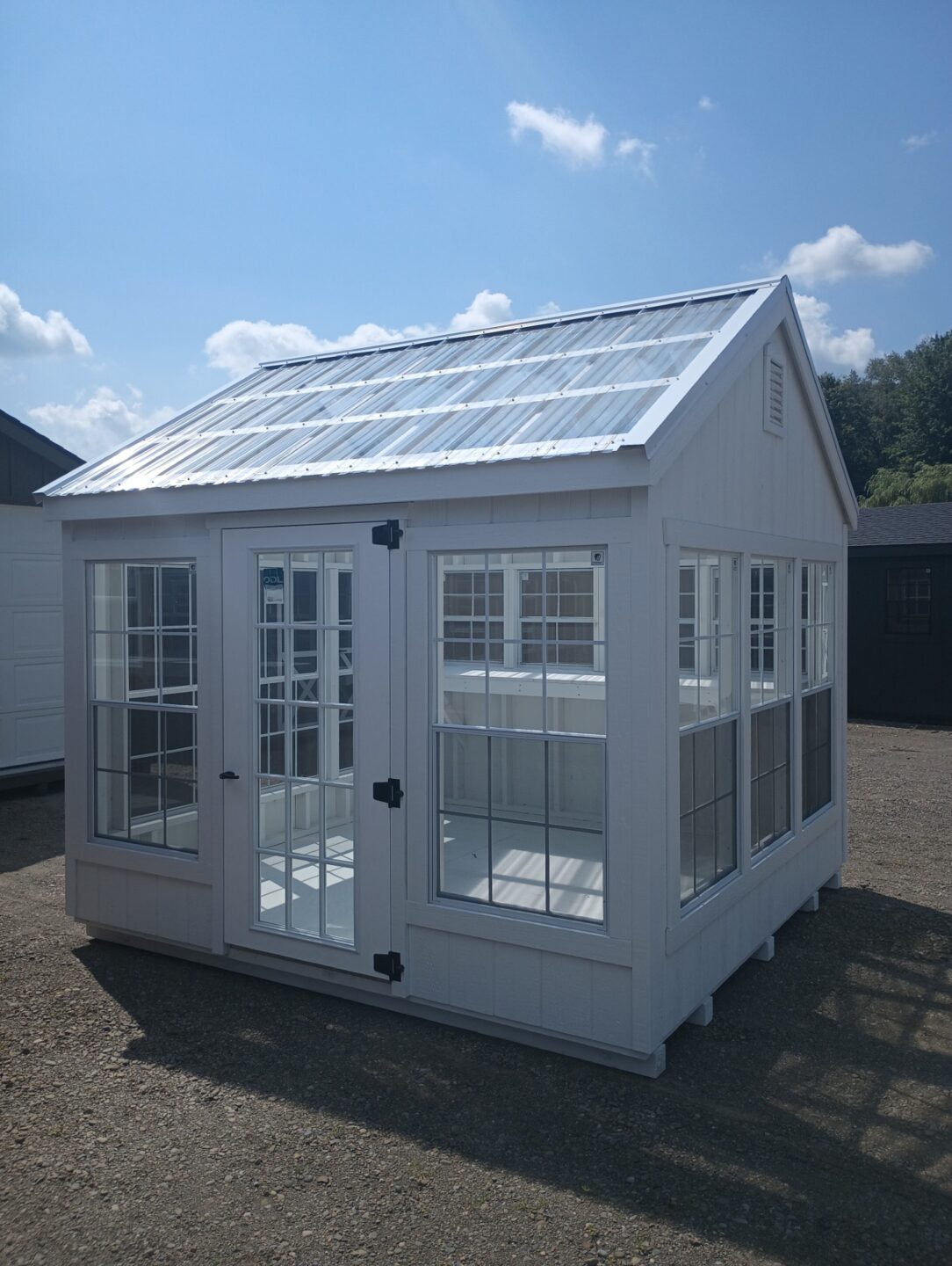 Small white greenhouse with lots of windows, glass doors and clear roof panels