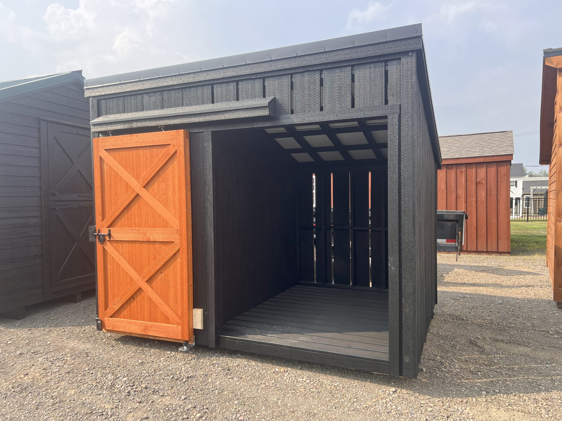 Small firewood shed with one side open and stained sliding door on other side