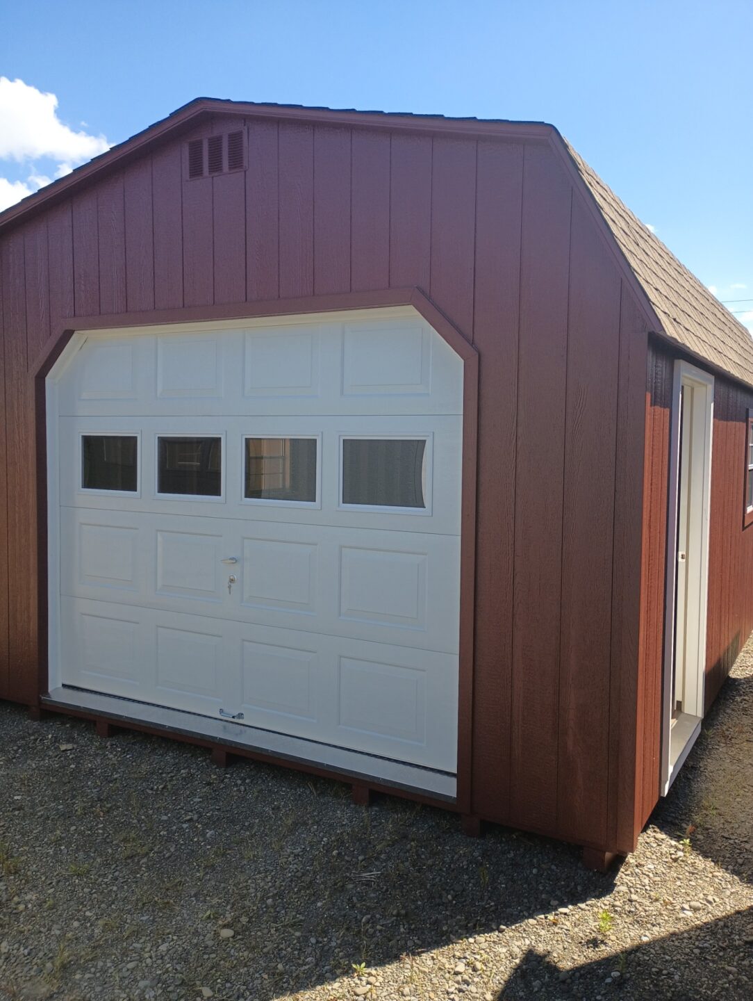Red garage with white overhead door with glass, side door and two windows