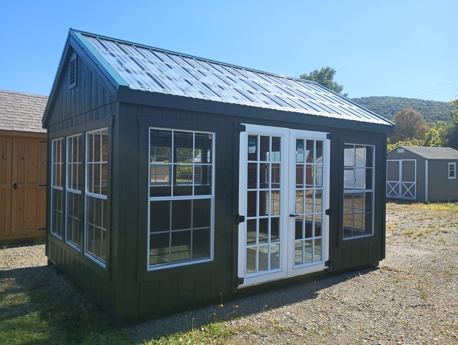 Greenhouse with double glass doors, tons of windows all around and clear roofing panels