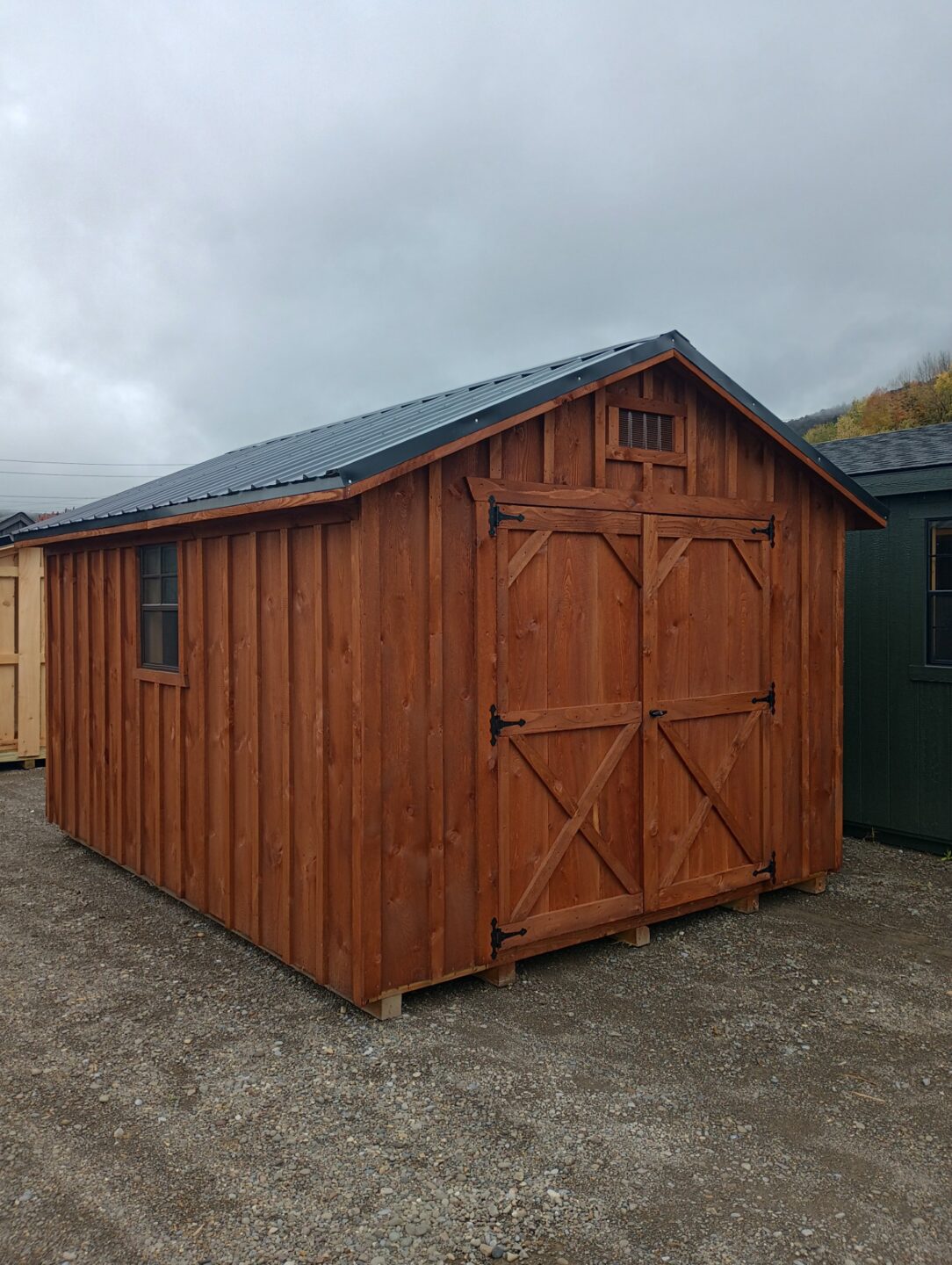 A frame style shed with board and batten siding, metal roof, double doors and windows on each side