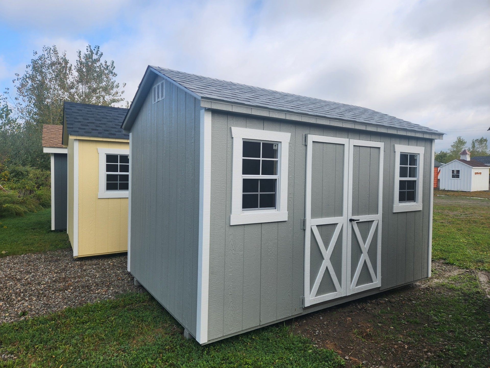 Gray a frame style shed with double doors and windows on front with shingled roof
