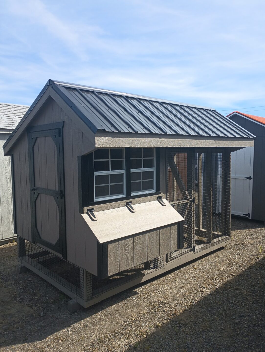 Clay chicken coop with black trim and black metal roof with roost area and run area attached