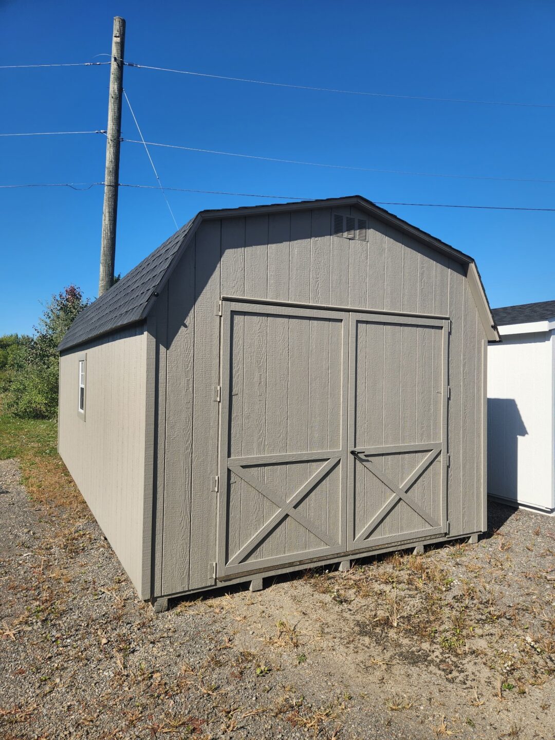 Large barn style shed with oversized double doors, gable vents, windows and shingled roof